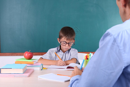 坐在黑板背景课堂上的中小学生和教图片