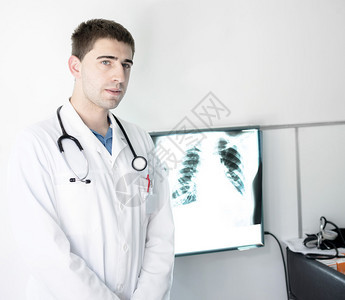 站在肺部X射线图像旁边的年轻医生图片