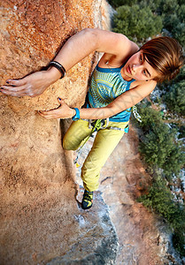 女攀岩者爬上石墙图片