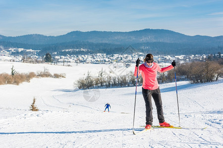 妇女穿越滑雪攀登一个斜坡和另一图片