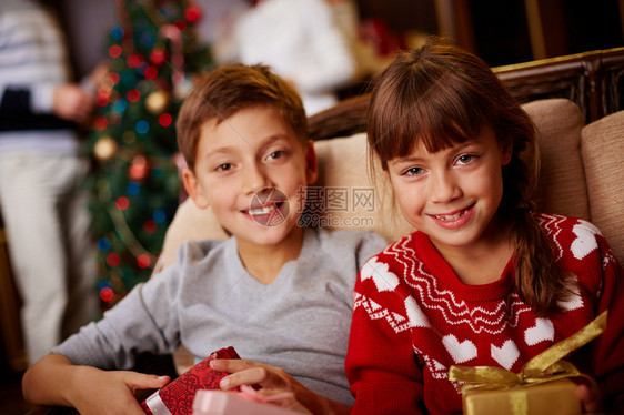 两个快乐的孩子的肖像圣诞礼物看着摄影图片