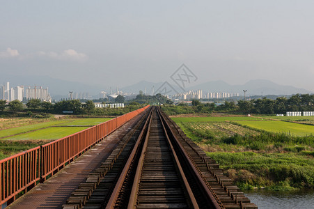 一条废弃的铁路在一条河对面的农场道上被带往图片