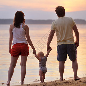 日落时分在沙滩上幸福的三口之家图片