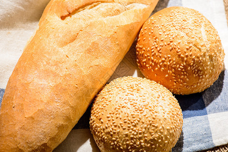 给你最新鲜的面包方格餐巾纸上新鲜出炉的自制芝麻卷和法式面图片