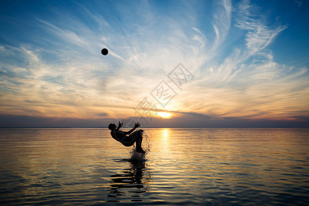 日落时人们在海里玩球图片
