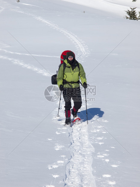 穿着雪鞋和登山杖的人在山上图片