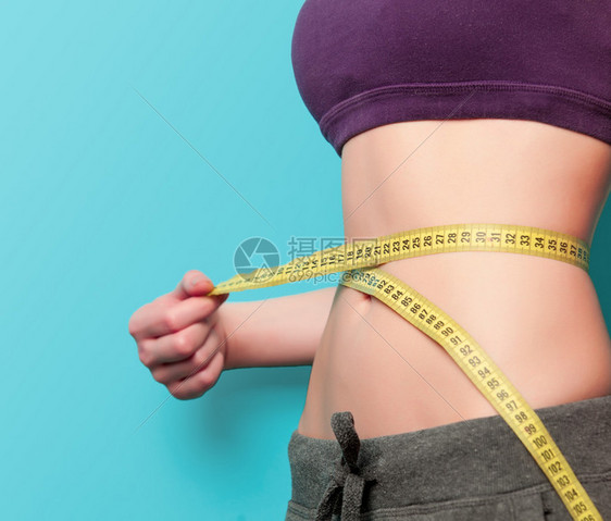 蓝色背景的妇女用体积显示其腹肌图片