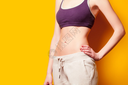 在黄色背景下减肥后展示腹肌的女人图片