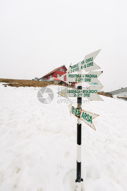 罗马尼亚滑雪度假村上方雪地中的木制路标图片