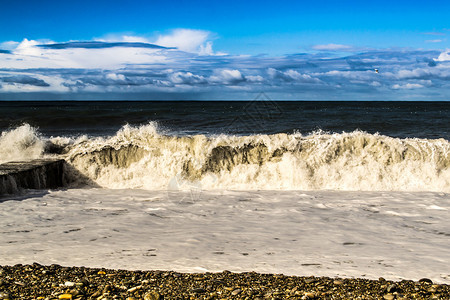 坠落的海浪落在石头沙滩上随着云图片