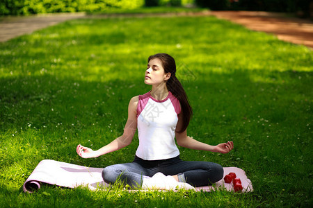 运动中的年轻女子在阳光下放松在绿公园图片