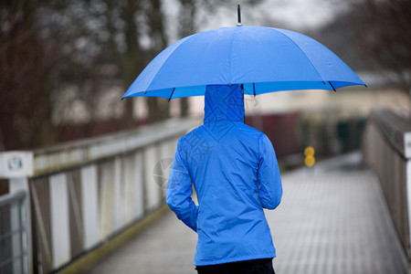 一个在雨中撑着伞走路的人图片
