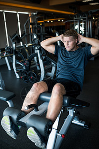 在健身房做仰卧起坐的运动型男人图片