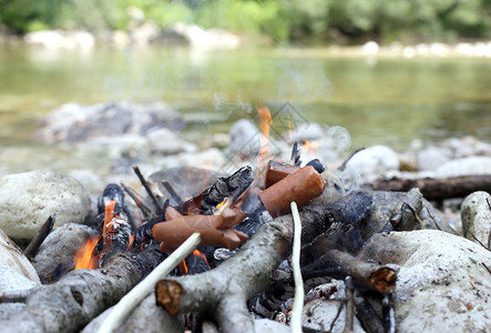 在山河边煮肉和香肠的户外篝火背景图片