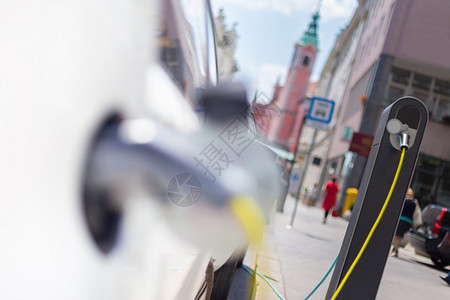 电动汽车充电源城市街道上的城市电动汽车充电站关闭插入正在充电的图片