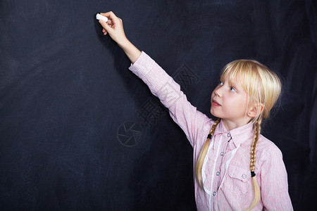 学校儿童在黑板上用粉笔写作图片