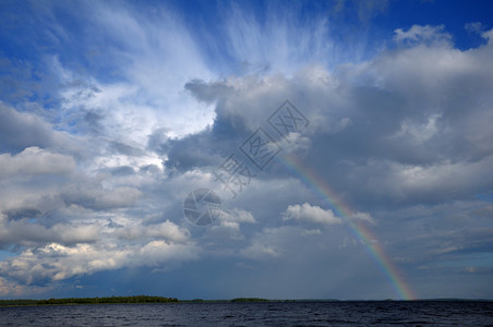 图片显示湖面天空中美丽的云层下饱和的彩虹图片