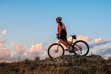 骑自行车的人在日落时分在山上骑自行车图片