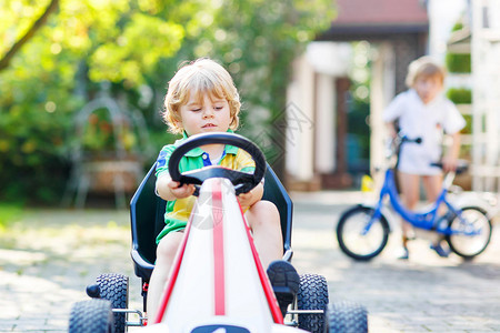 3岁的活跃小男孩在夏花园户外驾驶踏板车图片
