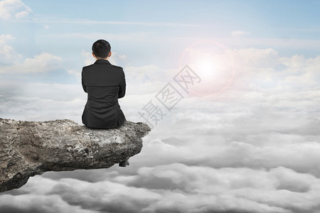 坐在悬崖上天光下云彩背景的图片