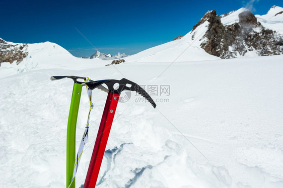 一对冰斧卡在雪中背景是山脊图片