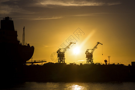 日落时的造船厂起重机和船的剪影图片
