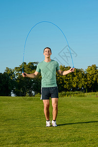 家伙在绿色草地上跳绳从事体育运动的家伙做运动的人图片