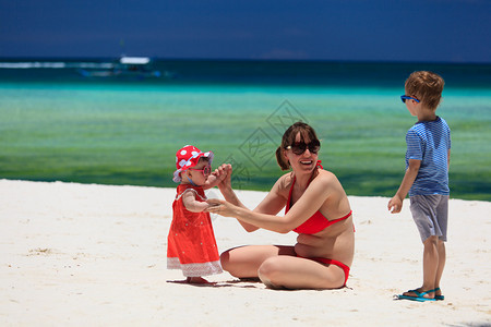 母亲带着孩子在热带沙滩上玩耍图片