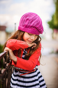 穿着红色贝雷帽的美丽笑容小女孩在城市公园的背图片