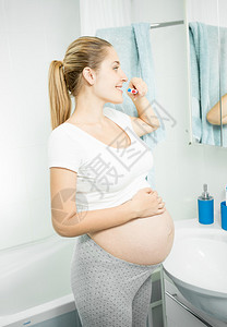美丽的孕妇在浴室刷牙图片
