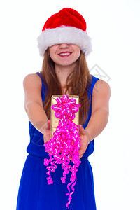 戴着圣诞帽子的年轻快乐女孩站在室内拿着巨大的圣诞节礼图片