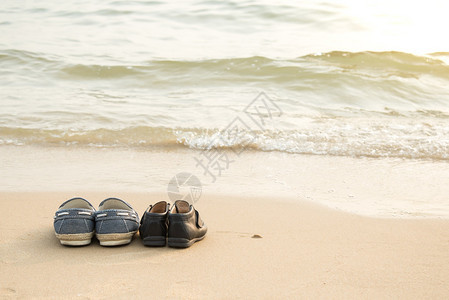 远处的鞋和儿子的鞋在海滩上的沙滩上有复制空间图片
