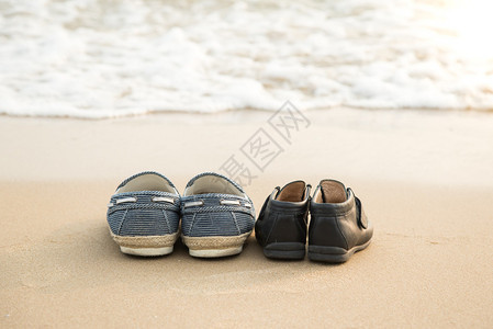 远处的鞋和儿子的鞋在海滩上的沙滩上图片