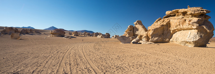 高海拔的土路与沙质漠和安第斯高地风景秀丽的岩层背景图片