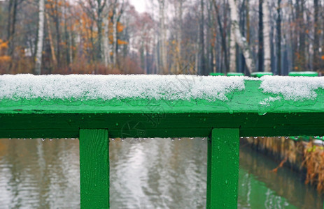深秋或初冬农村地区河流桥梁的绿色木扶手上的雪和雨分段图片