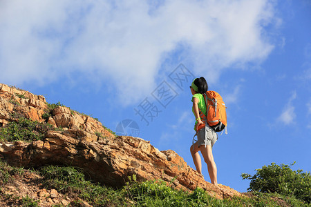 年轻女子背包客爬上山峰图片