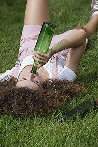 女孩啤酒瓶在公园的草地上铺图片