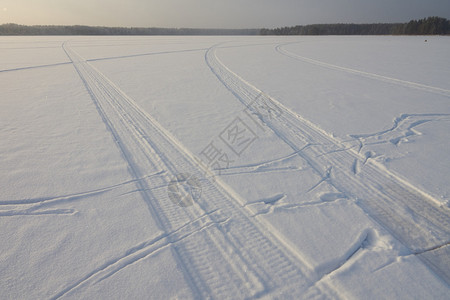 乡村冬季结冰湖雪上的雪地摩托痕迹图片