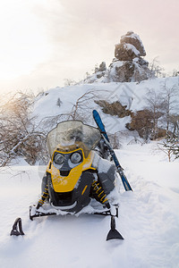 雪地摩托和滑雪在日落时的山脉背景图片