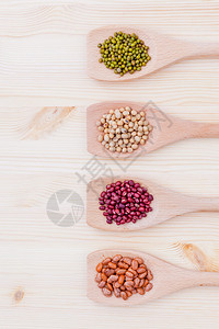各种样的豆子和小扁豆在木制背景上的木勺大豆绿豆红图片