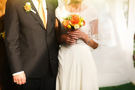 新郎和新郎站在橙色木拱门附近举行婚礼图片