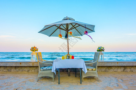 空桌和沙滩浪漫晚餐的椅子图片
