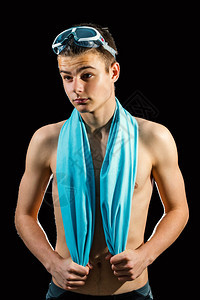 穿着蓝毛巾的年轻男游泳运动员的近距离摄影棚肖像在黑人背图片