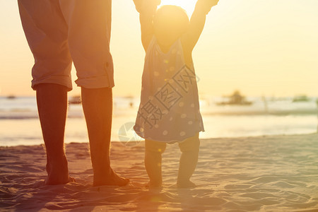 侧脸剪影父亲和海滩上的小女儿的剪影背景