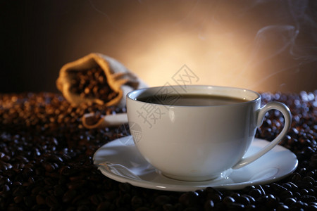 深色背景中咖啡豆中的一杯热咖啡图片