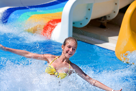 在水上乐园的水上滑梯上快乐的少女暑假图片