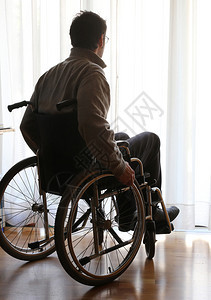 残疾人坐在窗前房间的轮椅背景图片