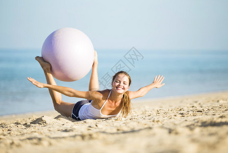 健康的女人与练习球在海滩图片