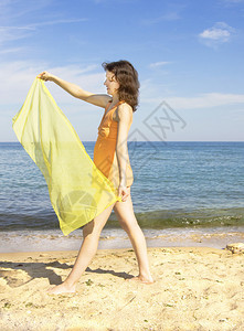 戴着黄围巾的年轻欧洲女人站在海边图片