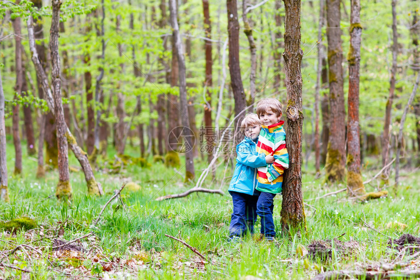 两个穿着鲜艳夹克的可爱微笑小男孩在雨天一起在森林里散步兄弟姐妹之间的友谊幸福的家庭图片